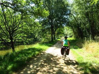 Jeune femme cycliste à vélo avec sacoche sur piste cyclable pour randonnée bicyclette le long d'un canal d'eau de rivière en France dans la Loire