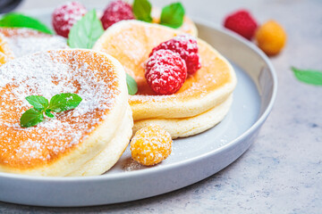 Japanese fluffy pancakes with raspberries in gray plate, gray background. Japanese cuisine concept.