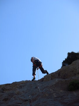grimpeur qui escalade avec casque et corde © Ourson+