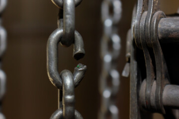 Broken chain link of a manual winch in an old factory building. Dark background. Blurred frame....
