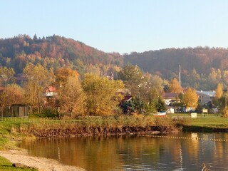 Fototapeta na wymiar lake on a background of mountains houses and autumn trees