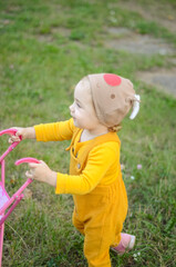 Photo of a toddler girl in the funny hat playing with a toy stroller