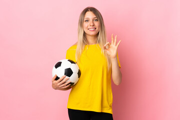 Young football player woman isolated on pink background showing an ok sign with fingers