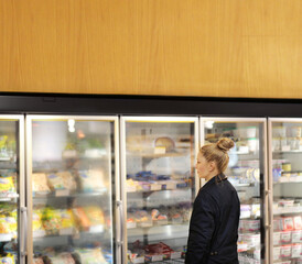 Woman choosing frozen food from a supermarket freezer	