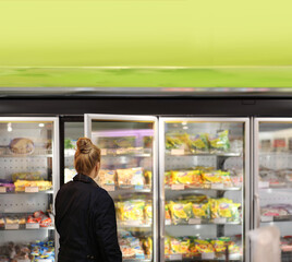 Woman choosing frozen food from a supermarket freezer	