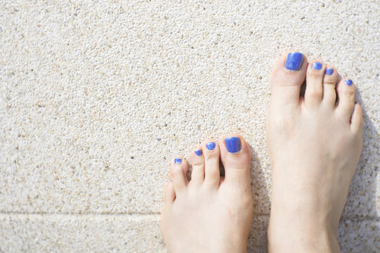 Womans feet with blue flip flops and blue painted toenails