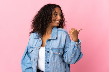 Teenager cuban girl isolated on pink background pointing to the side to present a product