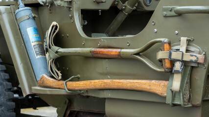 Detail of different work tools on the side of military vehicle. Shovel, Axe