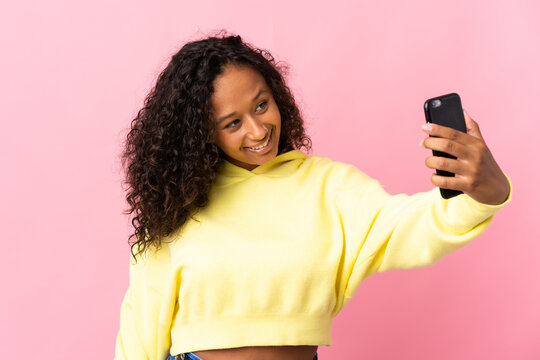 Teenager cuban girl isolated on pink background making a selfie