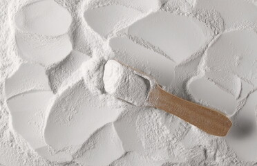 White sugar powder surface with wooden spoon, background and texture