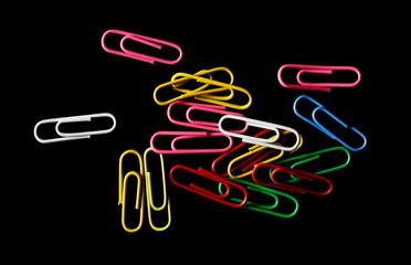 Colorful paperclips isolated on black background, top view