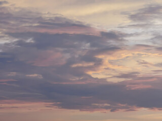 Cloudy sky at sunset in pink colors. The sun shines on the clouds. Color gradient. Sky texture. Abstract natural background.