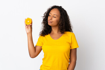 Teenager cuban girl isolated on white background holding an orange