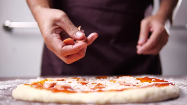 Baker hand making and prepare pepperoni pizza with sausage