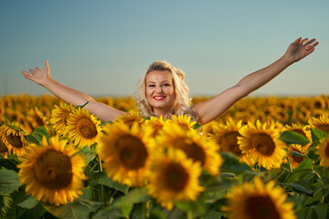 Fototapeta na wymiar Young attractive woman in a sunflower field at sunset