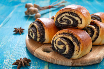 Tasty buns rolls with poppy filling on a blue wooden background.