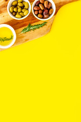 Green and black olives, olive oil in bowls on cutting board top-down copy space