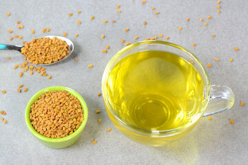 Fenugreek tea in a glass cup with fenugreek seeds in a bowl