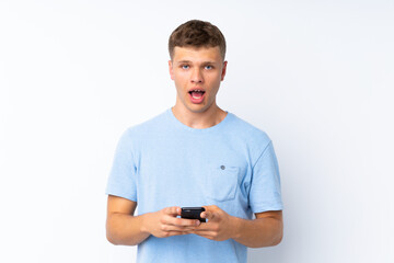 Young handsome man over isolated white background surprised and sending a message