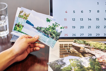 Close-up image of photographer showing printed photos from vacation he had last monthe