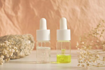 Fototapeta na wymiar Bottles of essential cosmetic oil in a glass bottle on a white table with a natural background. Aromatherapy oil, the concept of natural cosmetics. Space for text.