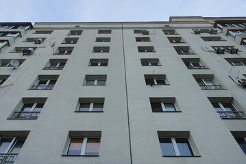 a row of windows on a gray concrete wall of a building against the sky