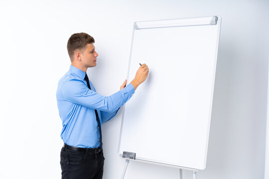 Young businessman giving a presentation on white board giving a presentation on white board and writing in it