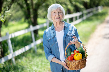 Smiling woman holding a basket of fresh seasonal vegetable