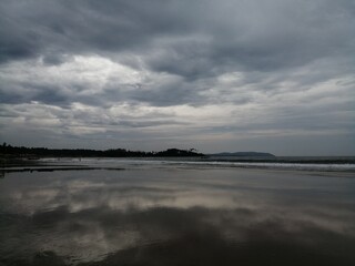 A Beautiful Beach View with an amazing landscape of mountains and clouds and boats and tourists