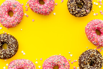 Frame of donuts with icing and sprinkles, overhead view. Colorful bakery