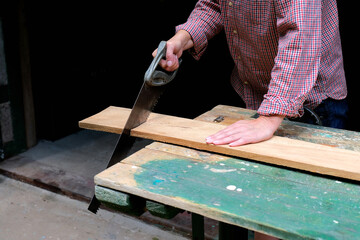 Craftswoman with hand saw cutting board. DIY, woodwork concept.