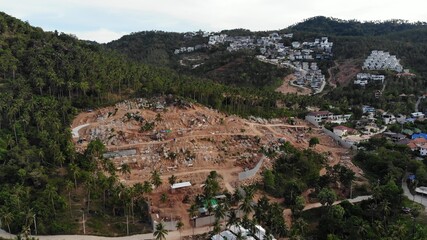 Tropical terrain covered with endangered forests and luxury villas. Drone view of large tropics with ecosystem disturbance due to buildings and deforestation. Koh Samui. Coconut palm plantations.