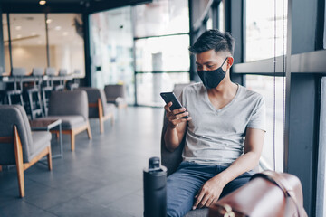 Attractive asian businessman with mask using smartphone at cafe. Drinking coffee and surfing the internet and read news. social distancing concept.