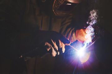 Male in face mask welds with welding