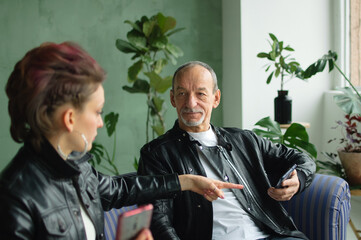Family portrait of adult daughter and senior father in loft room with houseplants. Man and girl are...