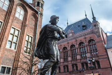 Fototapeta premium Statue of Flisak - Raftsman, Old Town City Hall and Arturs Manor building in Old Town of Torun historical city in north central Poland