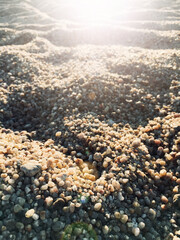 Sand beach texture background with rays of the sun. Detail of the grains of coarse sand with the background defocused.