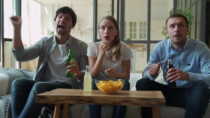 Funny friends celebrate the victory of their favorite team sitting on the couch - Powered by Adobe