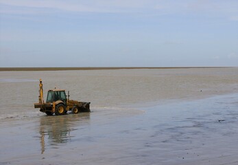 A tractor clearing silt from the flooded car park to make it ready for visitors at Mont-St-Michel, Normandy, France.