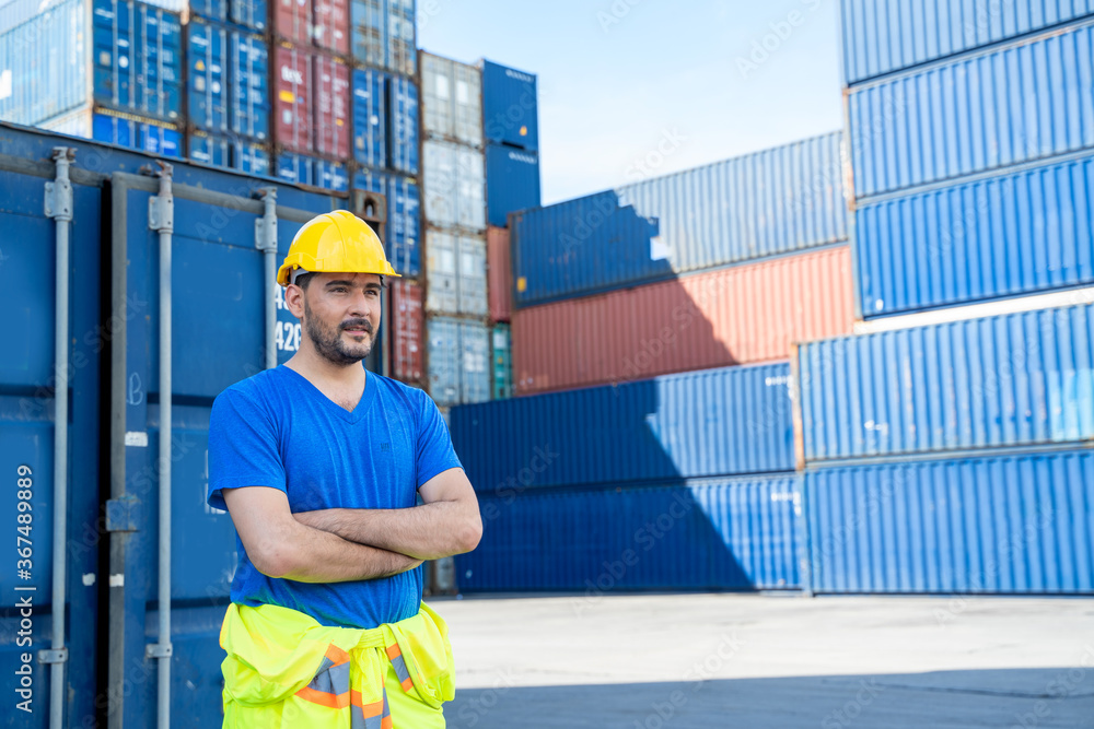 Poster portrait of container worker leaning on cargo container and looking up.