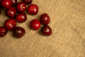 Ripe juicy cherries scattered on a homespun fabric with a rough texture. Close up.