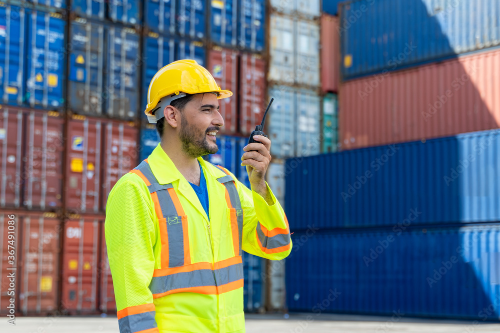 Poster container worker holding radio walkie-talkie to working checking at container cargo,import and expor