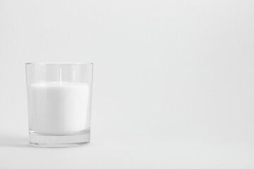 White candle in transparent glass on white background, mock up - obrazy, fototapety, plakaty