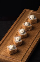Sushi rolls with sesame seeds on a wooden dummy board. Vertical orientation. Japanese traditional cuisine concept.