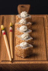 Sushi rolls with sesame seeds on a wooden dummy board. Vertical orientation. Japanese traditional cuisine concept.