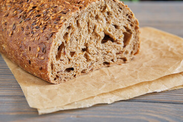 Fresh wholemeal bread with sunflower seeds, sesame and others grains on an old wooden table.
