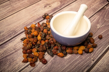 Ceramic mortar and dried rosehip fruit scattered on a wooden background. Close up.