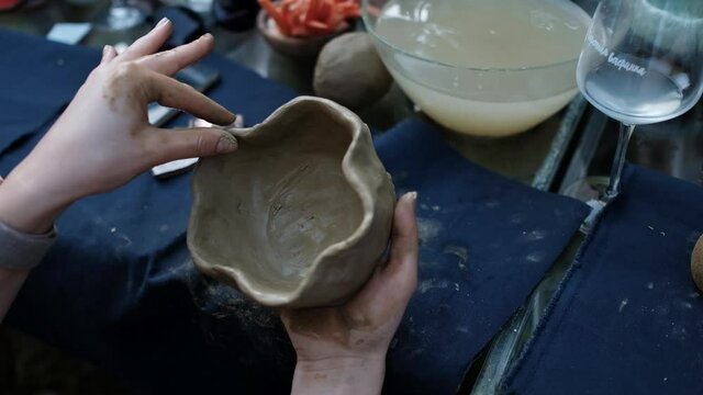 Close up of human hands making a clay bowl. Pottery teaching class.