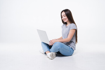 Young woman sitting on the floor with laptop isolated on white background