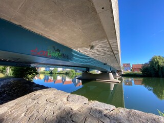 Brücke von unten Graffiti auf Beton,  Fluß Häuserreihe spiegelt sich im Wasser
